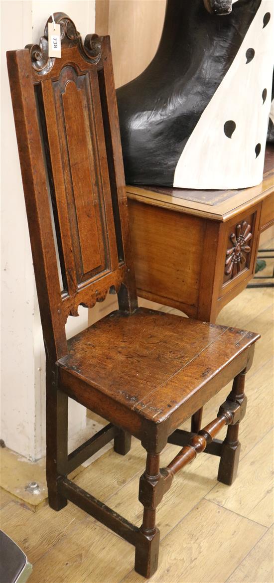 A mid 17th century oak chair, with panelled high back and scroll cresting, solid seat on turned and square legs
